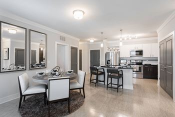 a dining area with a table and chairs and a kitchen in the background